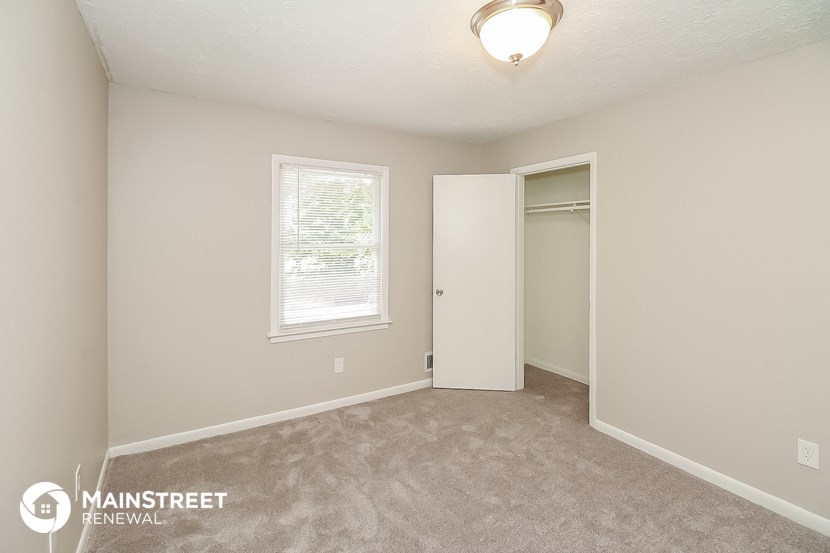 a bedroom with a door to a closet and a carpeted floor