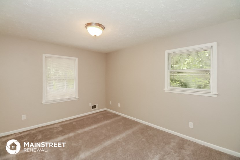 the spacious upstairs bedroom with carpeted flooring and two windows