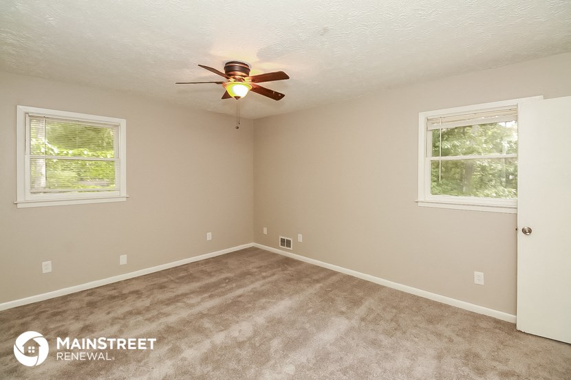 the master bedroom of this house has carpeted floors and a ceiling fan