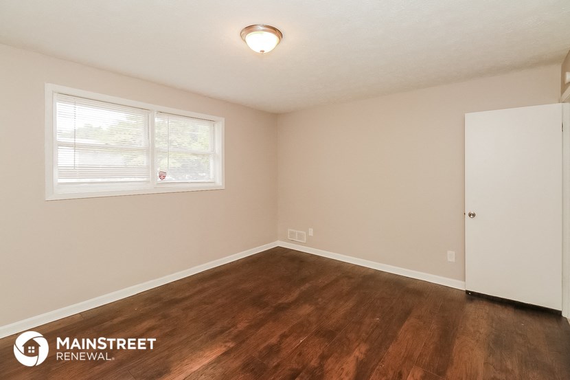 the interior of an empty room with wood flooring and a window
