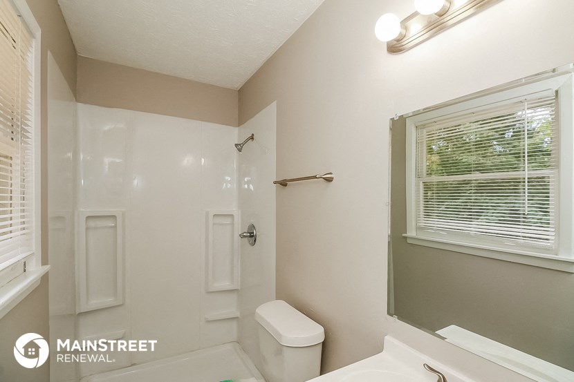 a bathroom with a shower toilet and sink and a window