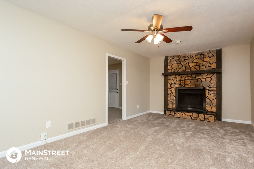 a living room with a fireplace and a ceiling fan