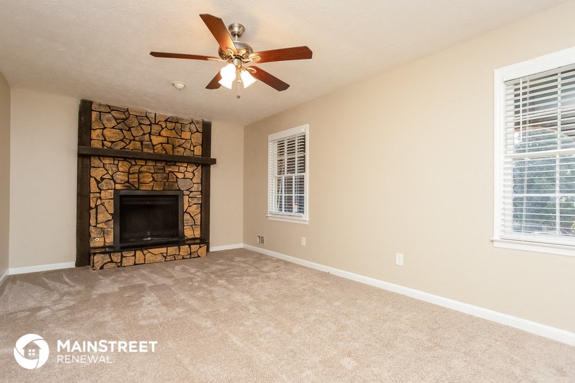 a living room with a fireplace and a ceiling fan