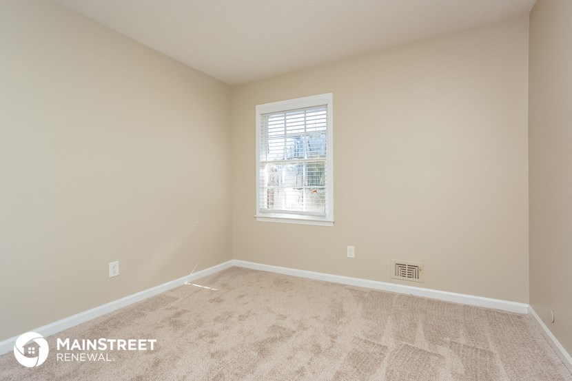 the spacious living room with carpeted flooring and a window