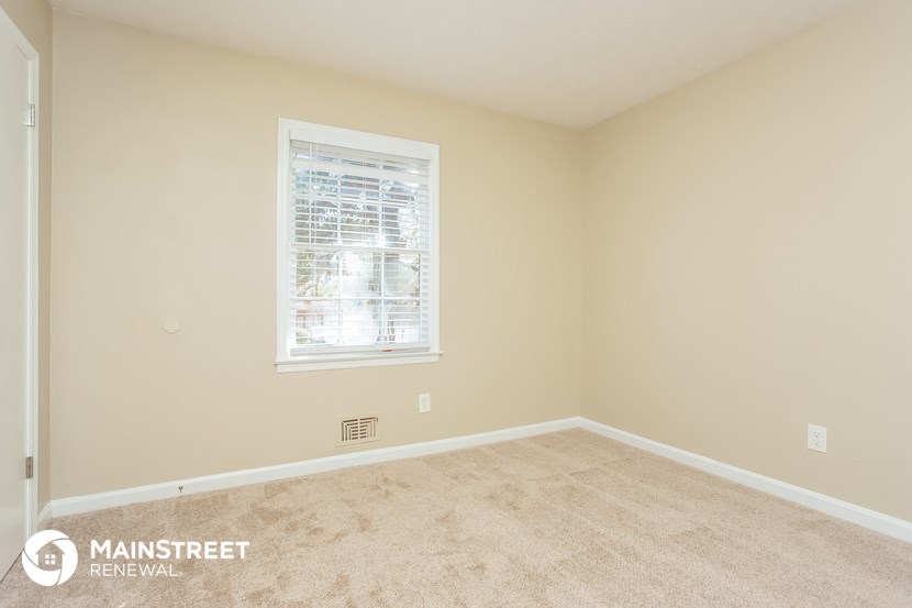 a bedroom with beige carpet and a window