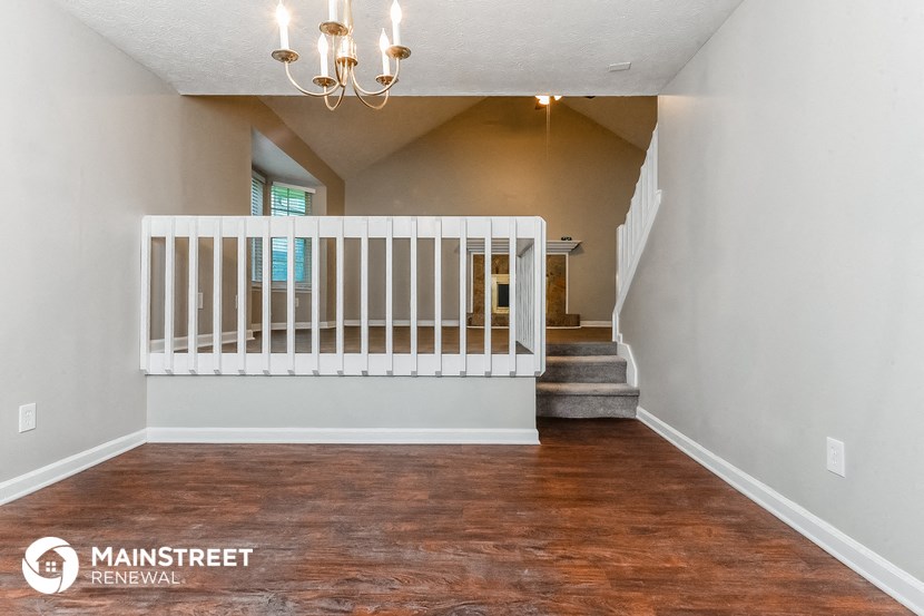 the living room of a home with a white crib and stairs