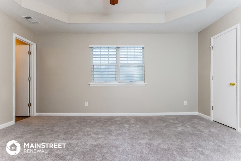 the bedroom of an apartment with carpet and a window