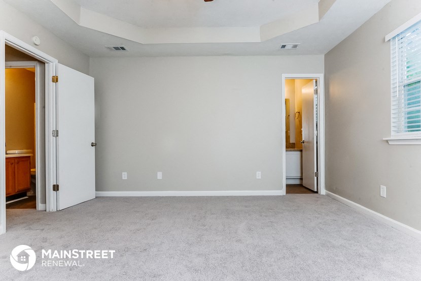 a bedroom with a carpeted floor and a door to a bathroom