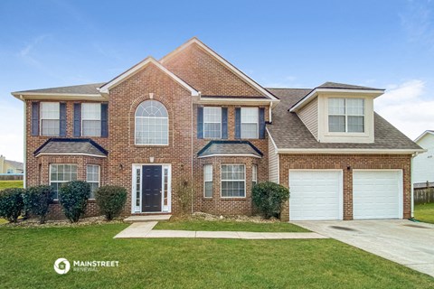 a brick house with two garage doors and a lawn