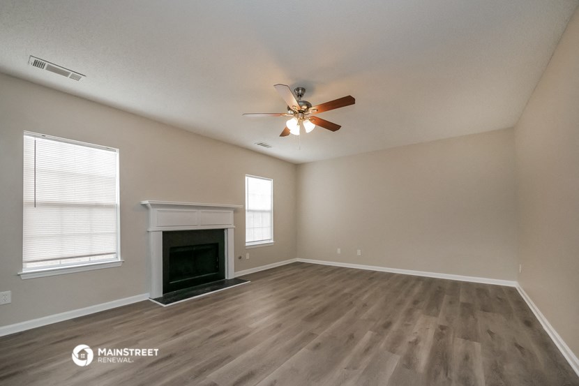 the spacious living room with fireplace and ceiling fan