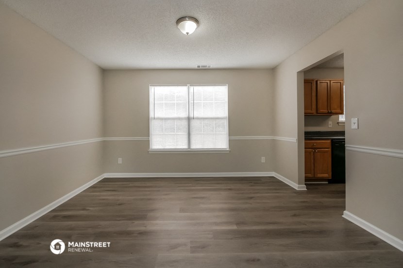 an empty living room with a window and a kitchen