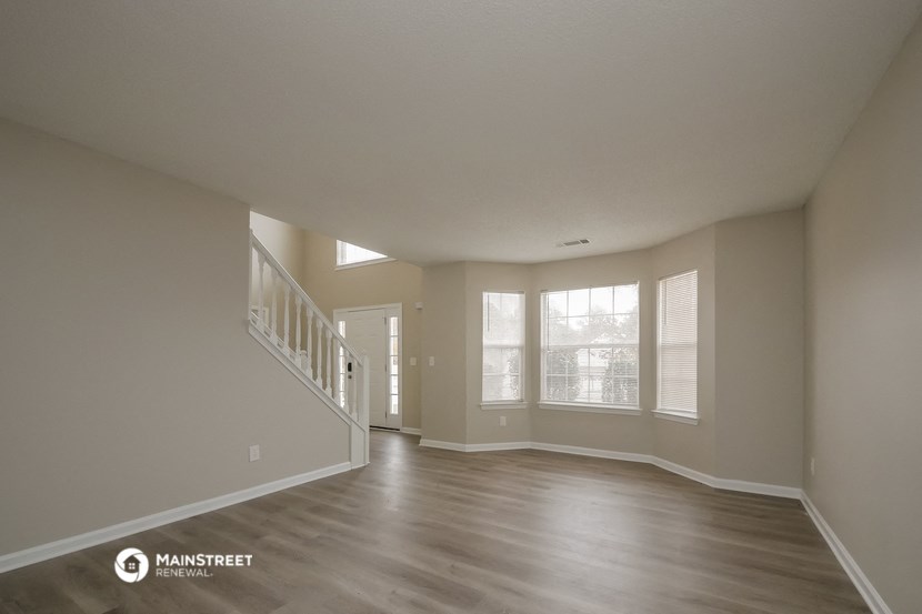 an empty living room with a staircase and windows
