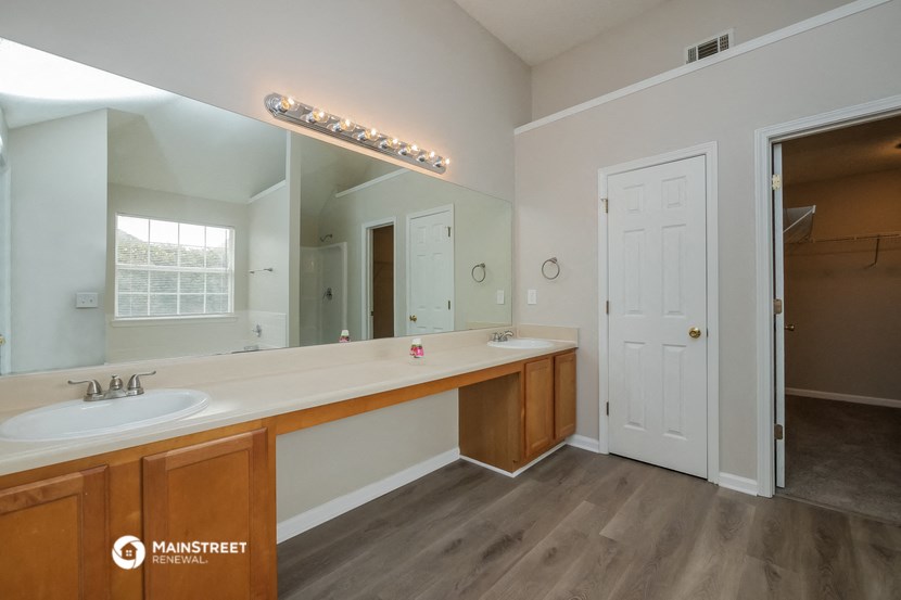 a bathroom with a large mirror and a sink and a door to a closet