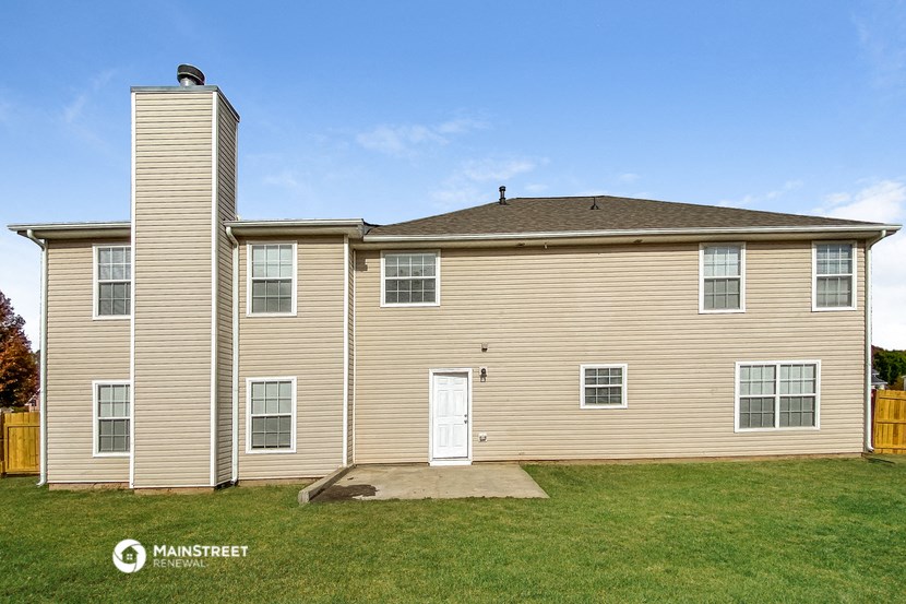 a tan house with a white door and a green lawn