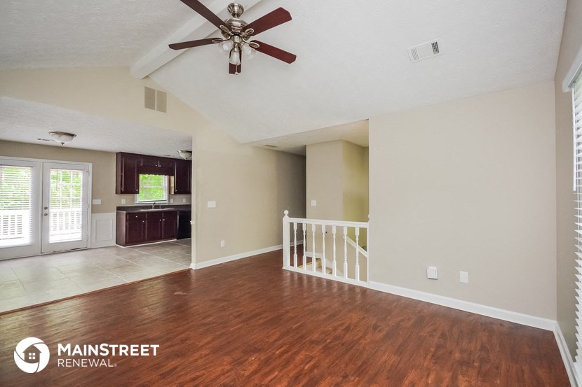 the living room and kitchen of an empty house with a ceiling fan