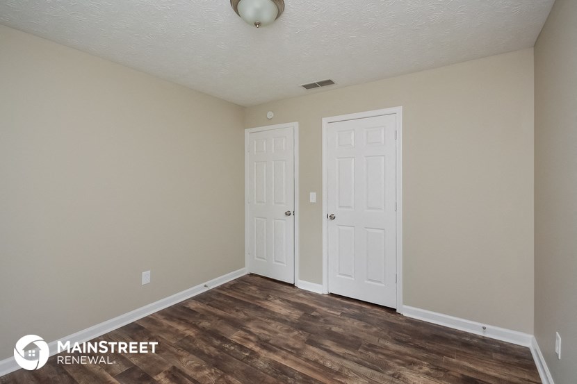 the upstairs bedroom with two doors and a hardwood floor