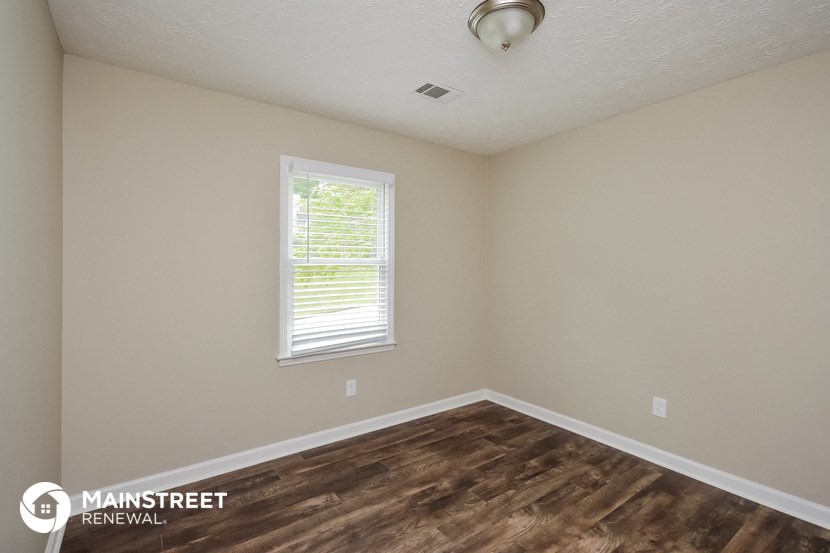 the interior of a bedroom with wood flooring and a window