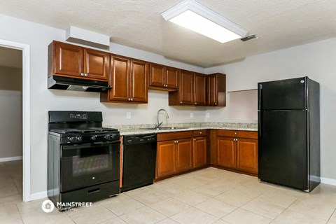 a kitchen with black appliances and wooden cabinets and a black refrigerator