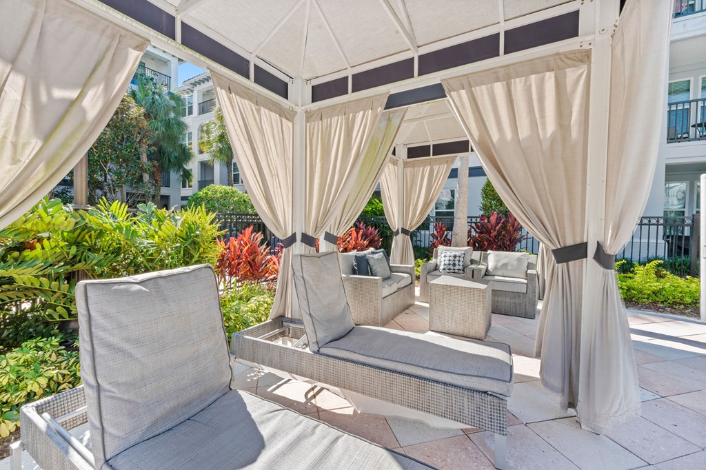 A patio with a white canopy and grey chairs.
