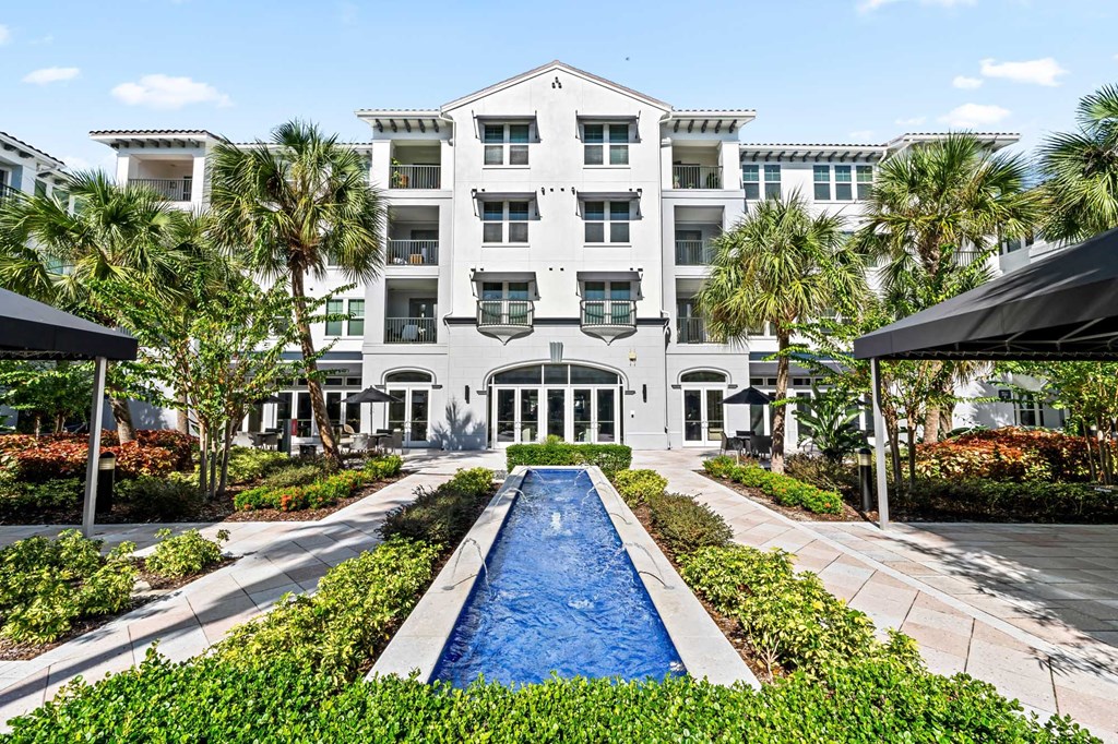 A large white building with a pool in front.