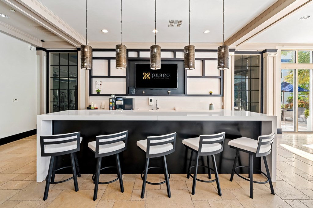 A bar with four chairs in front of it.