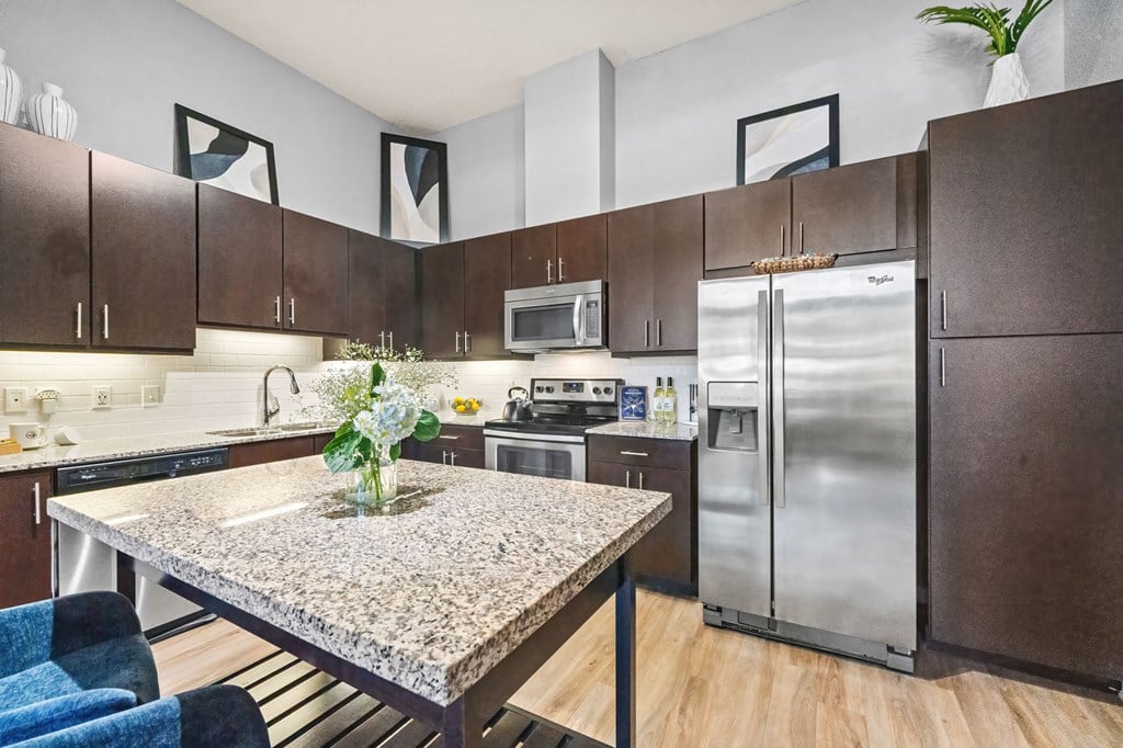 A kitchen with a granite table and stainless steel appliances.