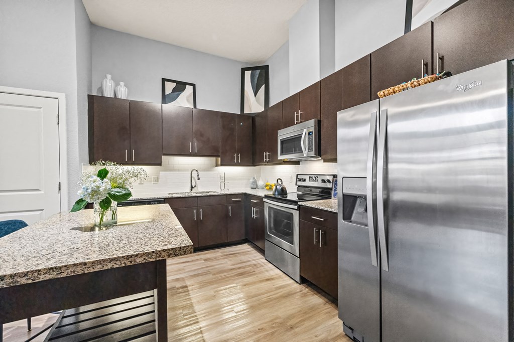 A kitchen with a granite counter top and stainless steel appliances.