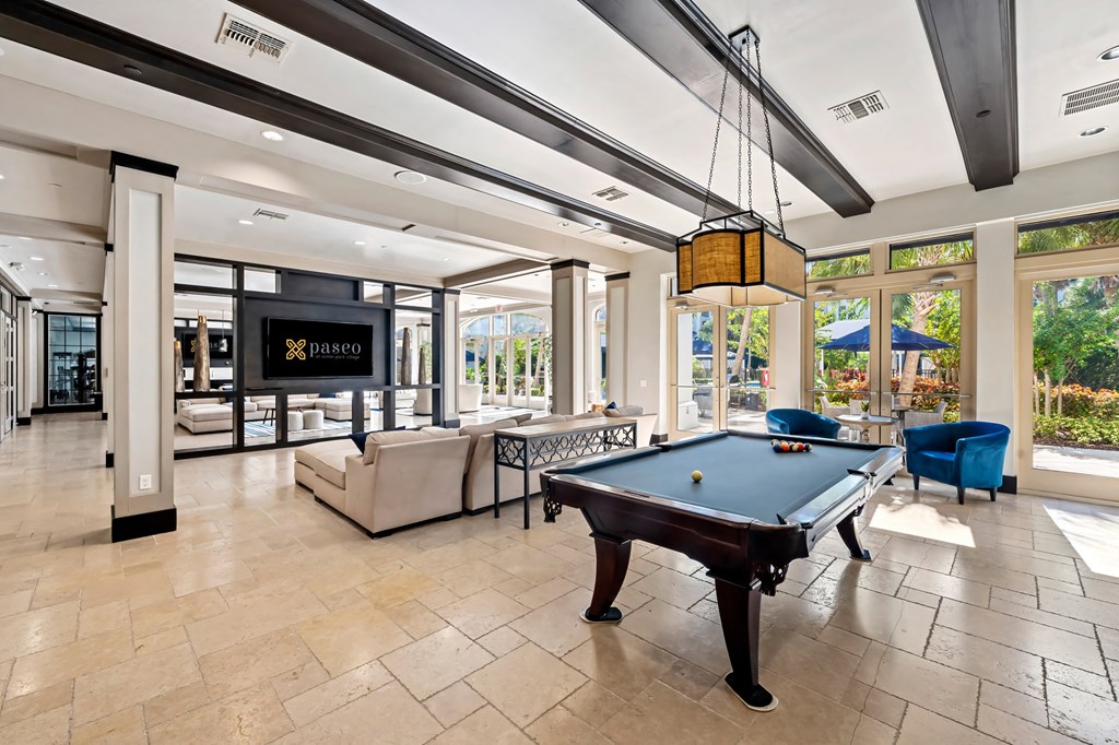 A pool table is in the middle of a room with a sign that says "PASADO".