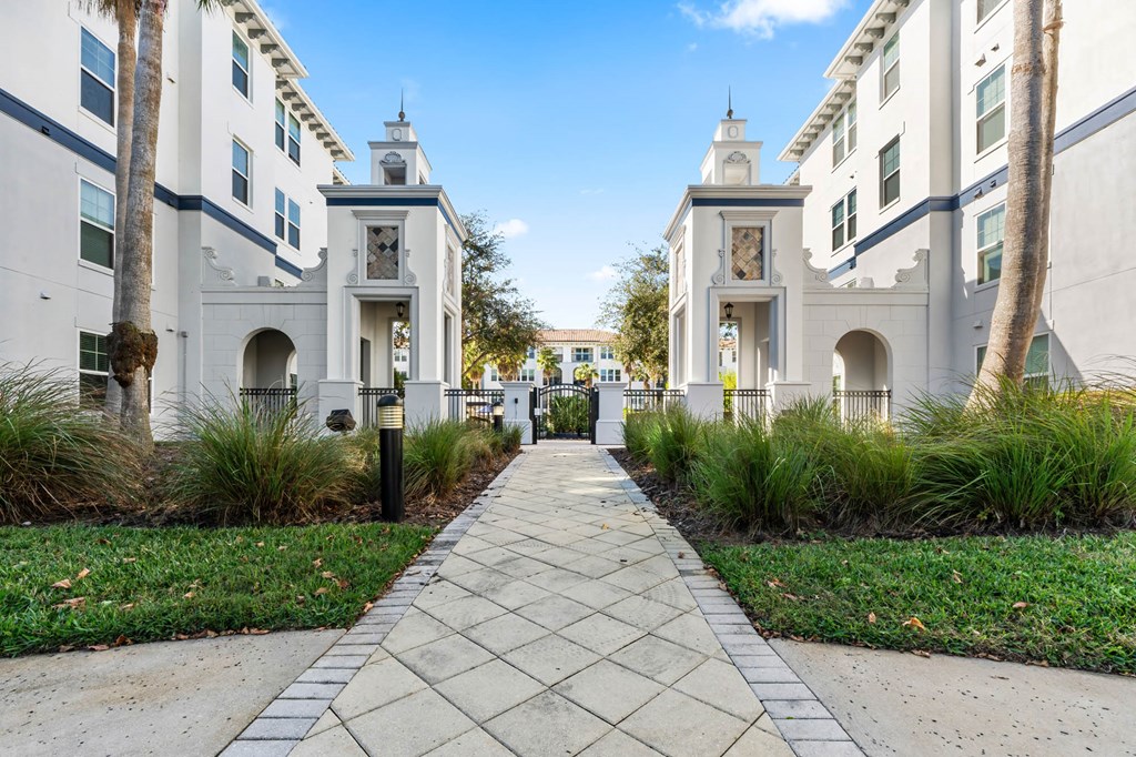 A long walkway between two buildings with palm trees on the side.