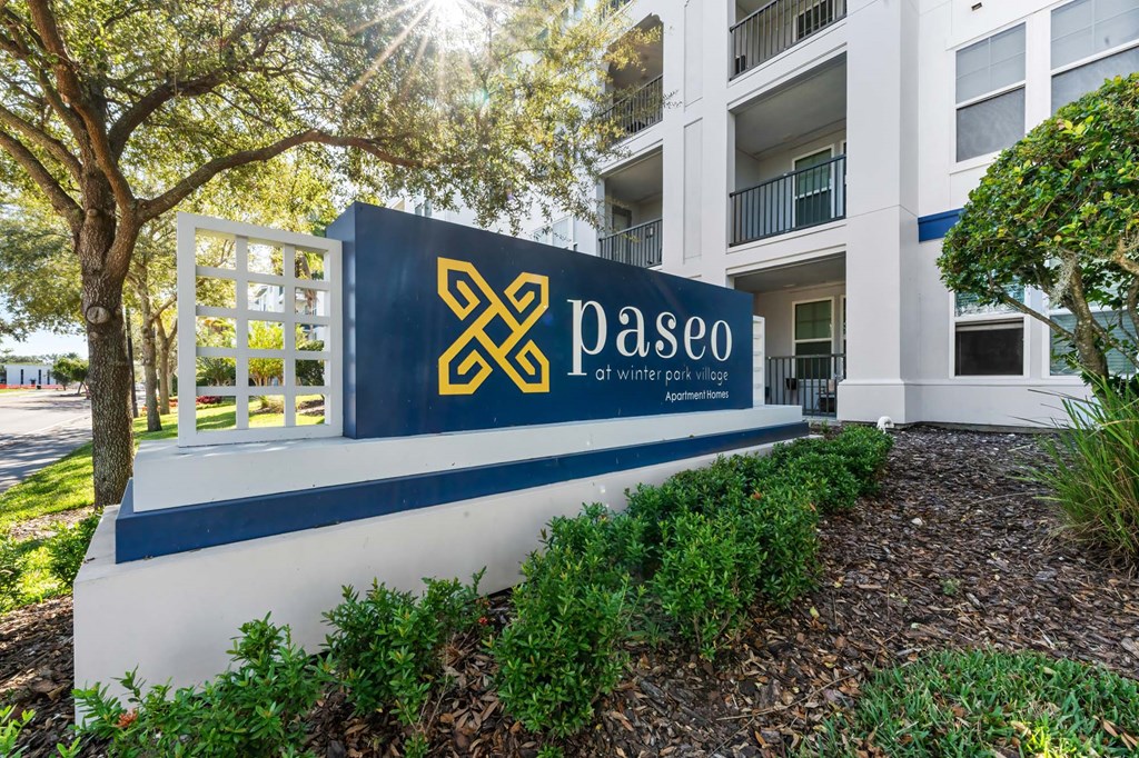 A sign for Paseo apartments is shown in front of a building.