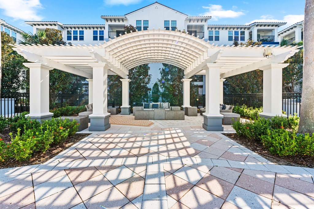 A white archway leads to a building with a black fence in the background.