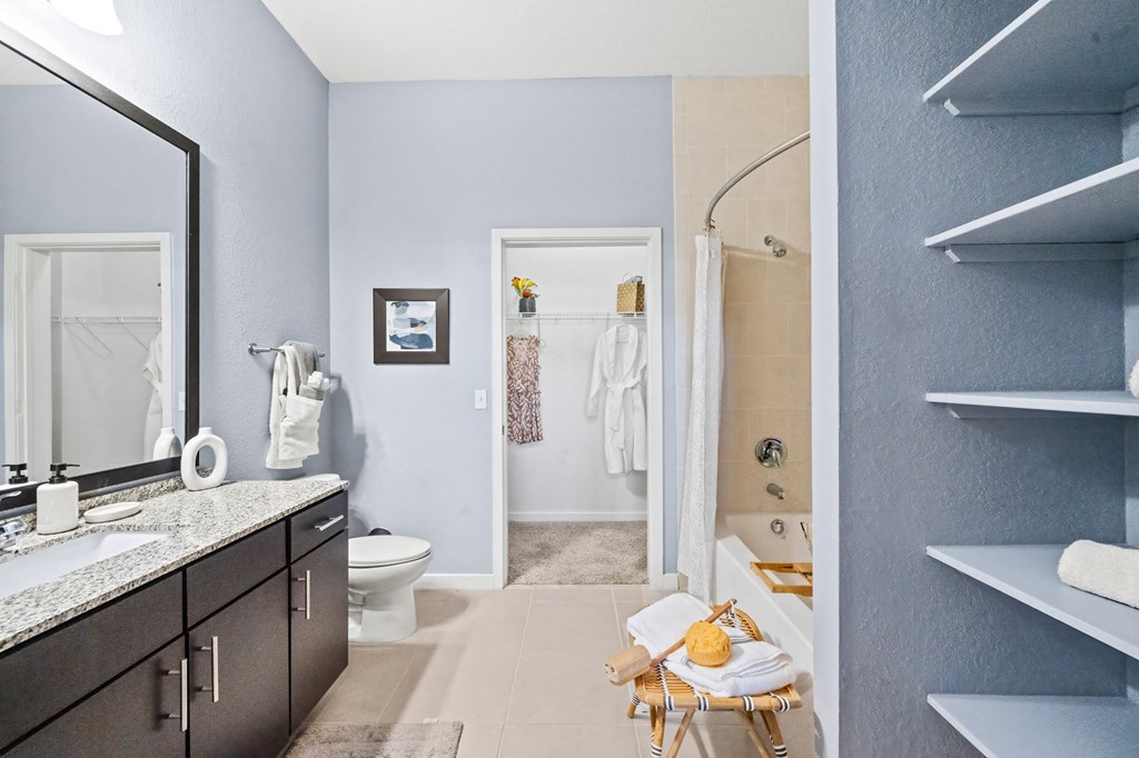 A bathroom with a toilet, sink, and chair.