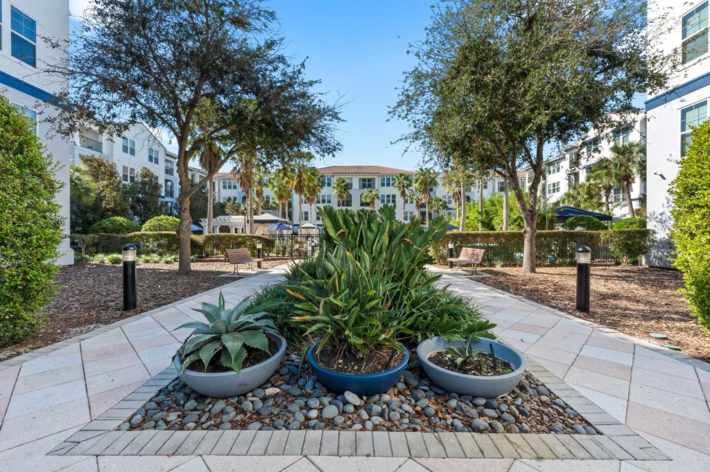 A garden with three potted plants in the middle of a pebble bed.
