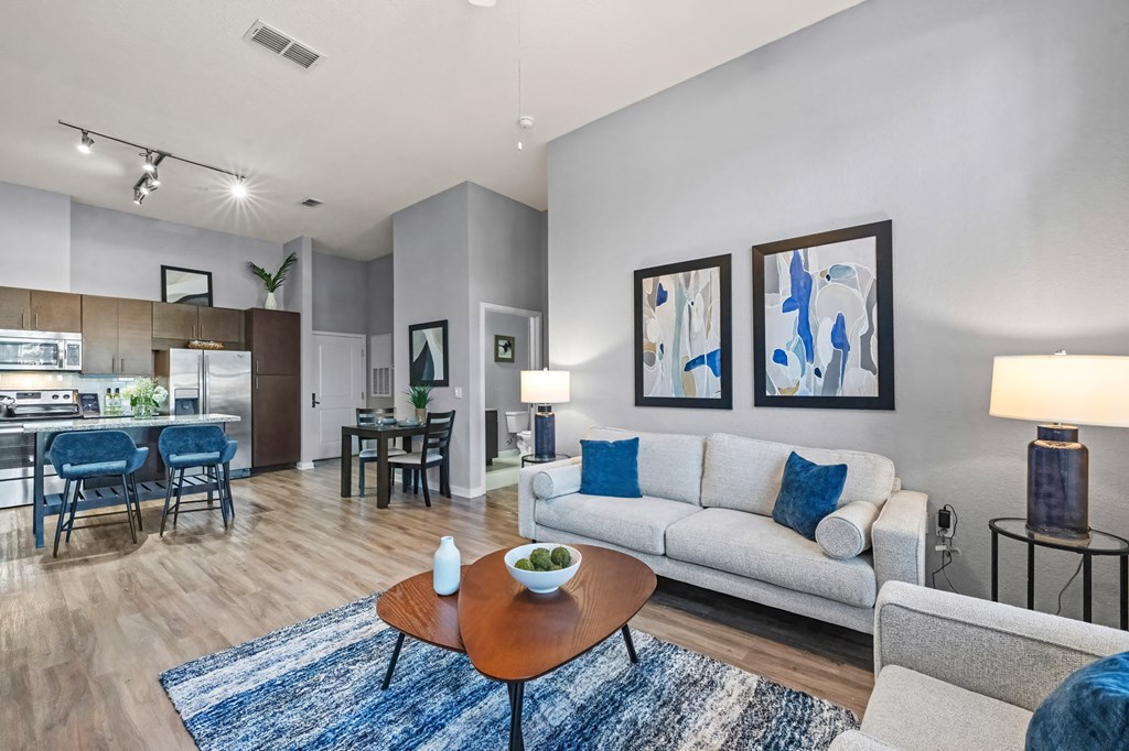 A living room with a white couch, a coffee table, and a dining table.