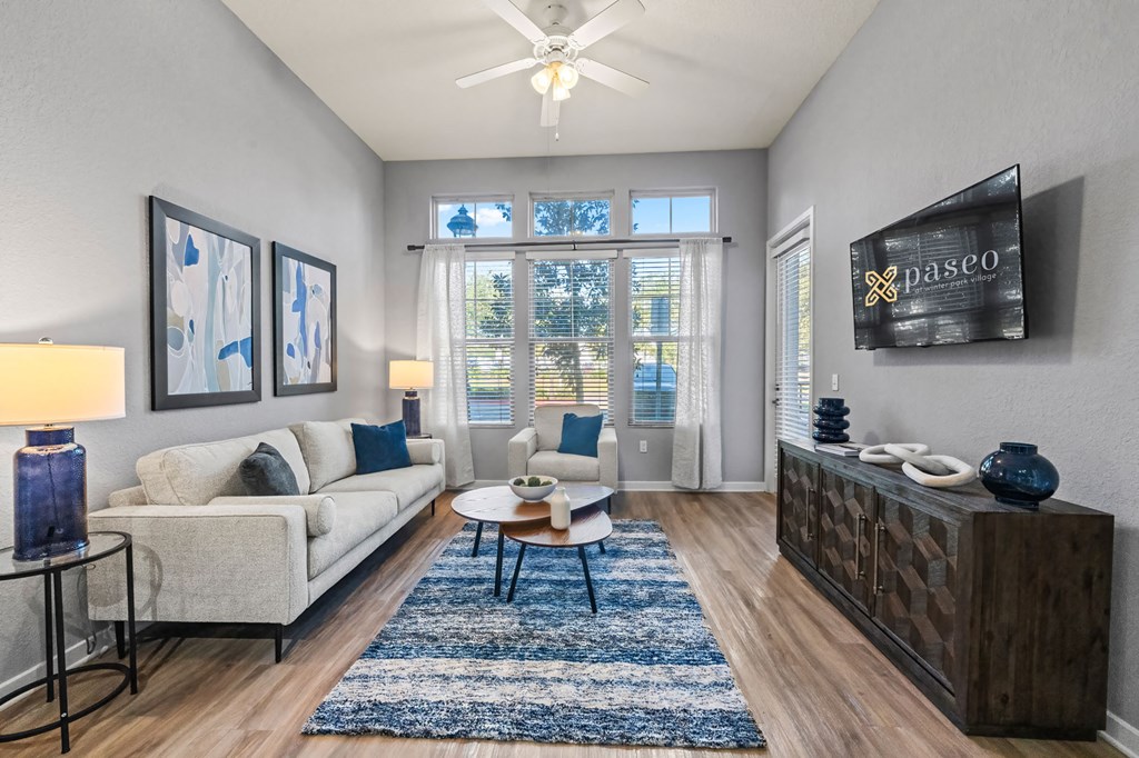 A living room with a white couch, a blue rug, and a wooden cabinet.