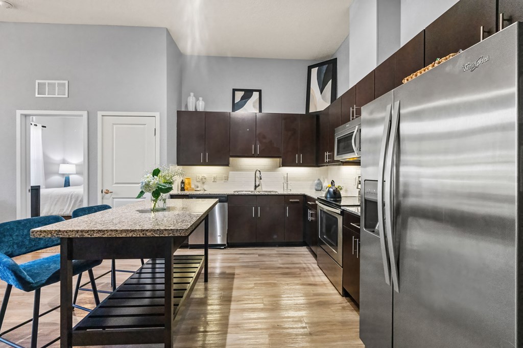 A modern kitchen with a large refrigerator and a dining table with chairs.