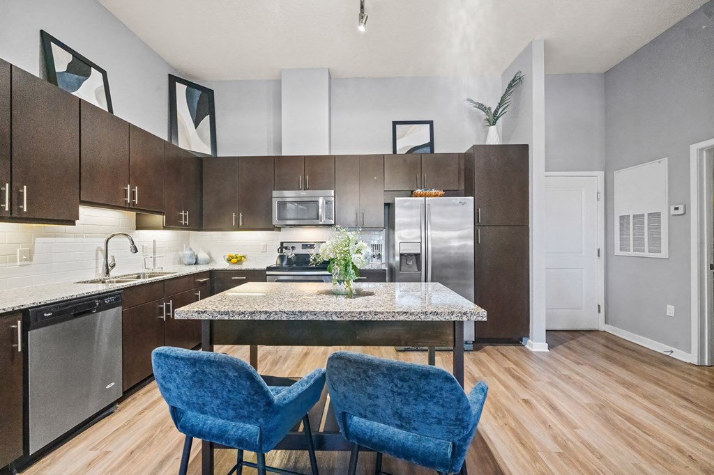 A kitchen with a table and two chairs.