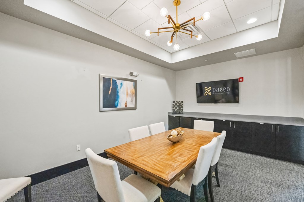 A dining room with a wooden table and white chairs.