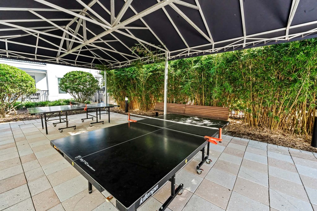 A ping pong table is set up under a white canopy.
