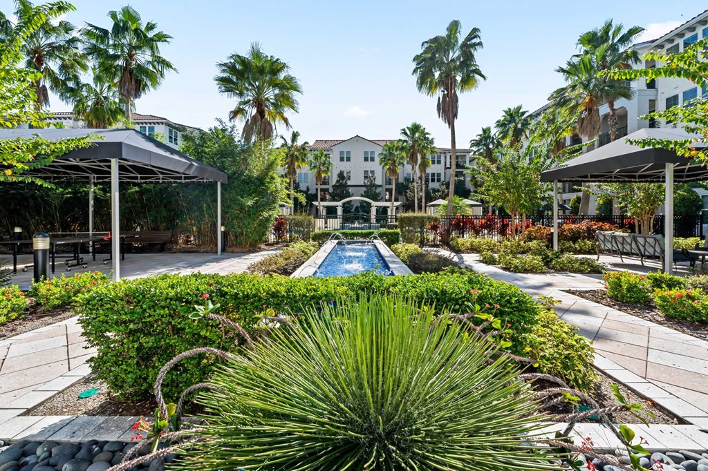 A pool surrounded by green plants and trees.