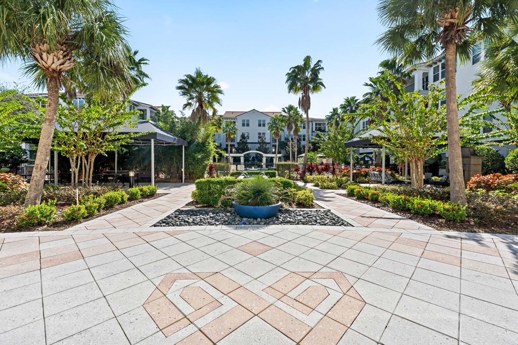 A garden with a patterned walkway and a fountain in the middle.