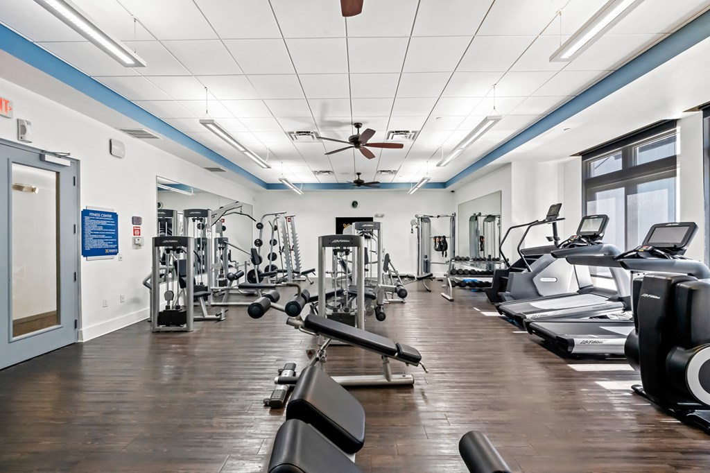 A gym with a variety of equipment including treadmills, weights, and exercise machines.