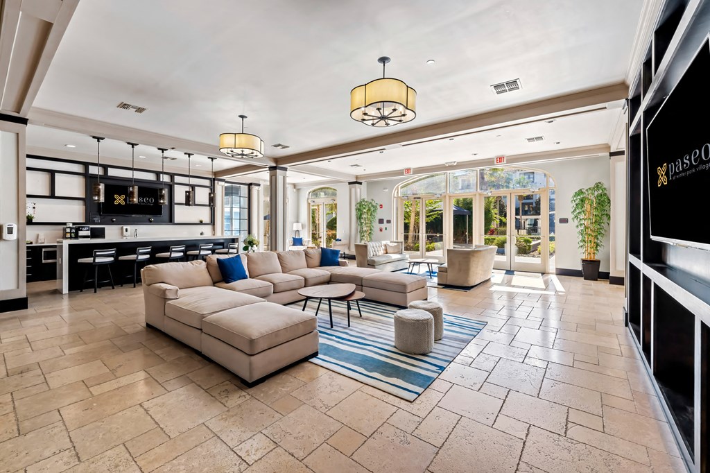 A spacious living room with a kitchen area in the background.