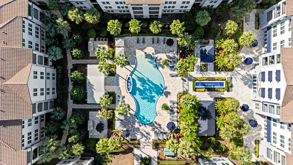 A bird's eye view of a pool surrounded by buildings and trees.