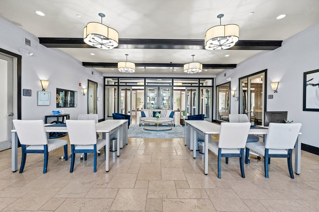 A dining room with a table set for six with white chairs and a view of the water outside.