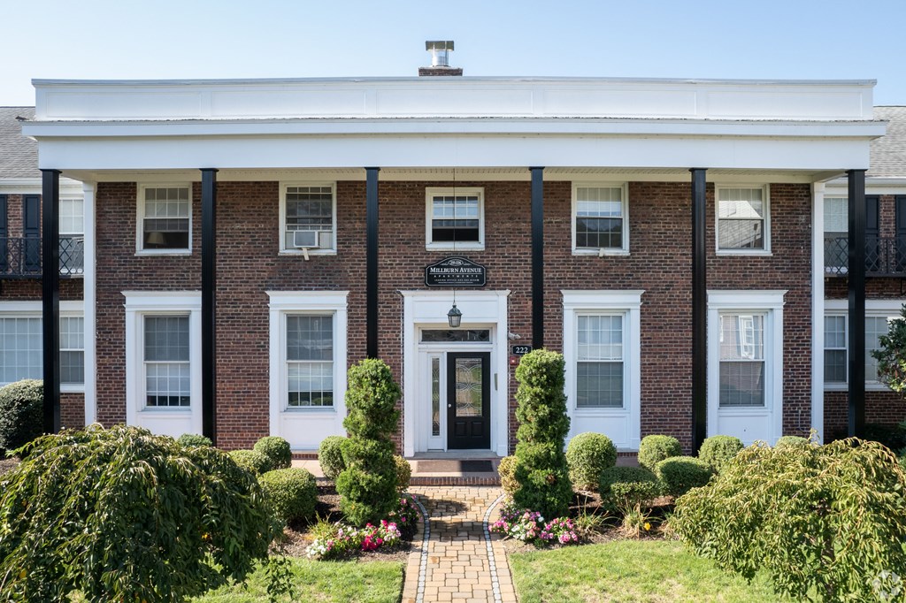 the front of a brick building with a white porch