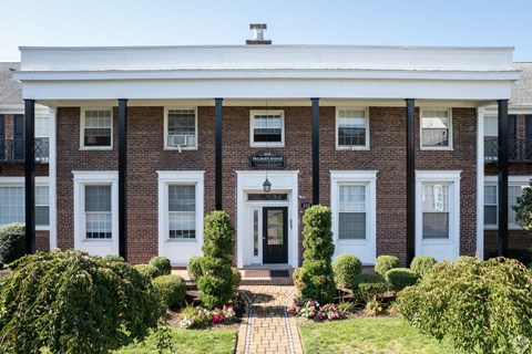 the front of a brick building with a white porch