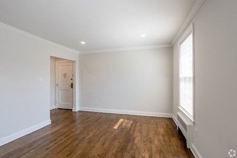 an empty living room with white walls and wood floors