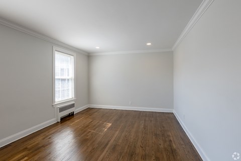 an empty living room with wood floors and white walls