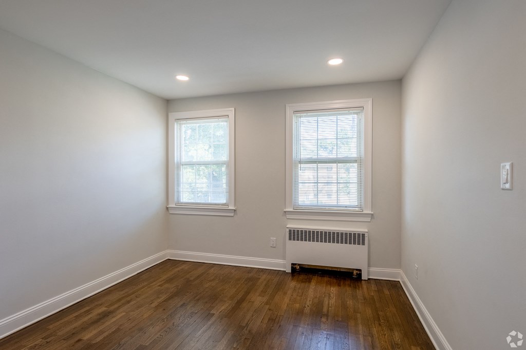 an empty living room with wood floors and two windows